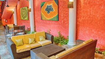 A lobby with a red wall, wicker furniture, and a ceiling fan.