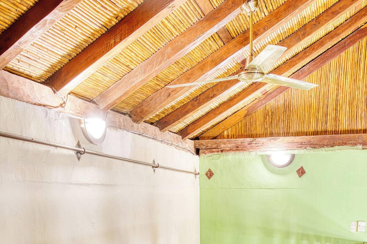 A room with two beds, a wooden table, and a ceiling fan.