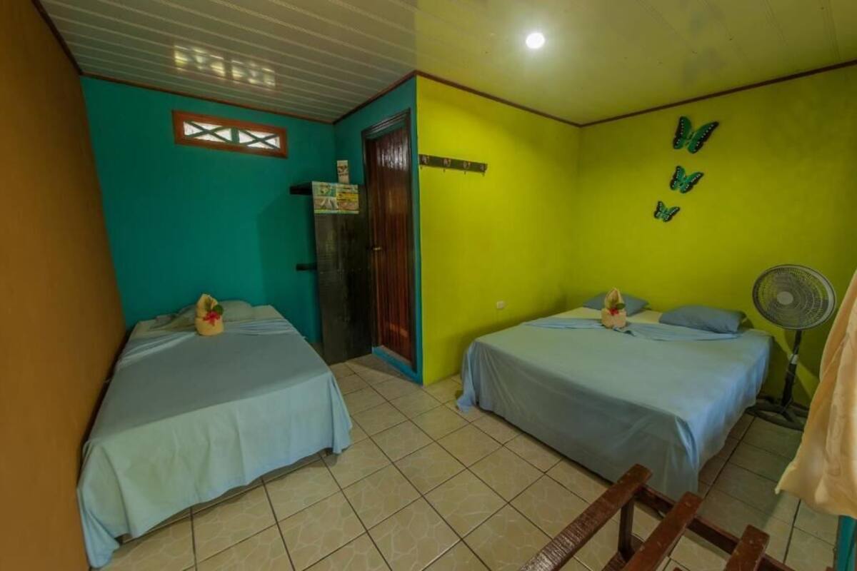 A room with two beds, a fan, and a window with a decorative frame.