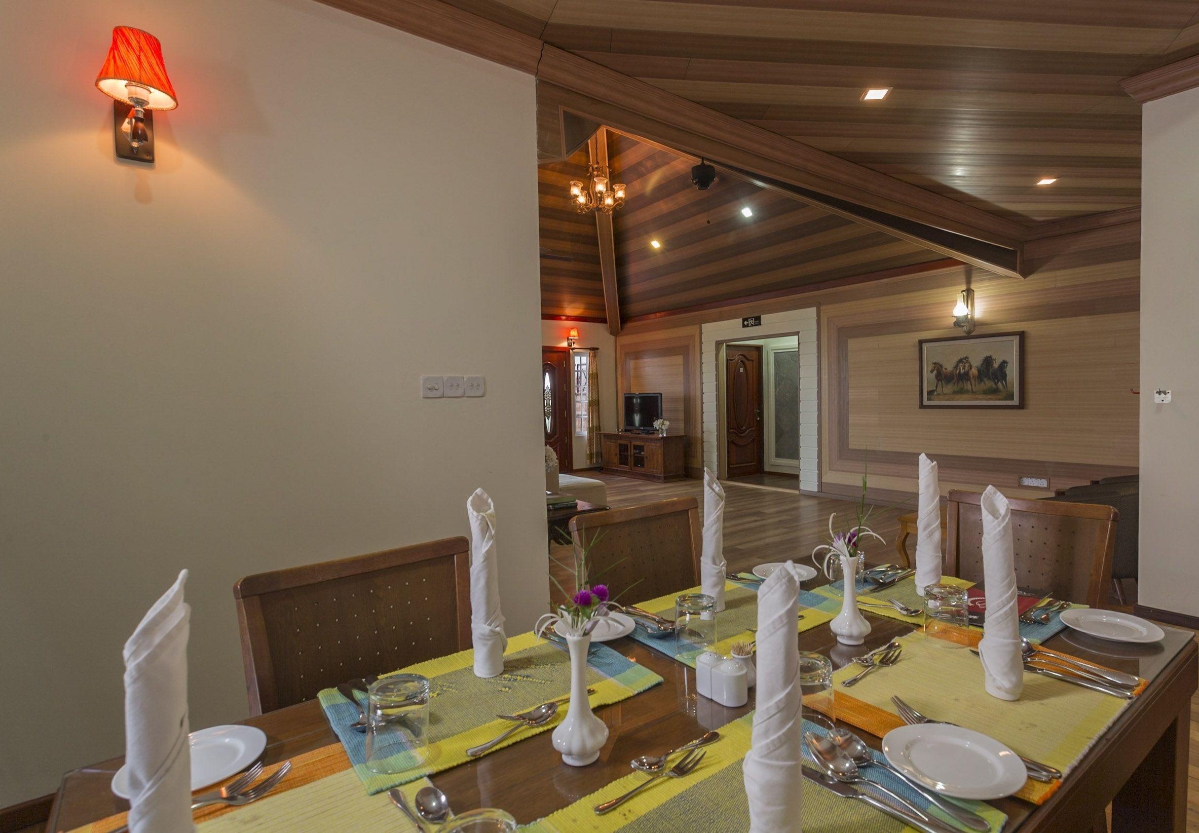 A dining area with a table set for four, including place settings, cutlery, and a vase with flowers.