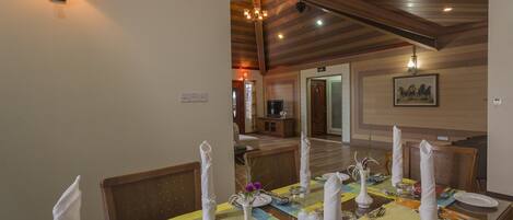 A dining area with a table set for four, including place settings, cutlery, and a vase with flowers.