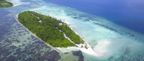 Privat strand, hvit sand, parasoller og strandhåndklær