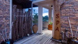 A wooden deck with a rustic fence, a large vase, and a wooden sign with the word "SPA".
