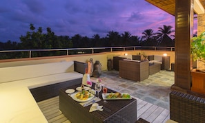 Relax on the patio with a sofa, two chairs, and a small table, surrounded by palm trees.