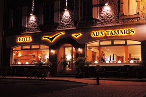 A hotel named "AUX TAMARIS" with a stone facade, large windows, and outdoor seating. - Hôtel Aux Tamaris - Vue Mer (Roscoff)