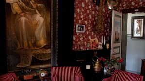 A room with a large portrait, red-striped chairs, a table with newspapers, a clock, and a vase with flowers. - Hotel Restaurant Vijlerhof (Vijlen)