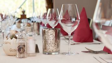 Une table dressée avec des verres à vin, des salières et des poivrières, et une bougie.