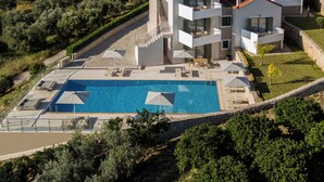 A modern multi-story villa with a swimming pool, outdoor seating, and a view of the surrounding landscape. - Anassia Villas (Nafplio)