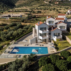 Una villa moderna de varios pisos con piscina, mobiliario exterior y vistas del paisaje circundante.