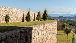 A stone wall with a grassy area and trees. - Anassia Villas (Nafplio)