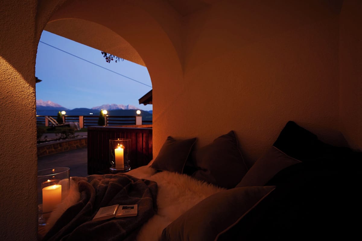 Ein gemütliches Zimmer mit einem Bett, Kerzen und Bergblick.