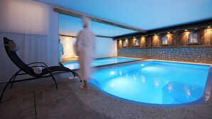 En swimmingpool med en stenvæg og en person, der går forbi.