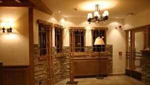 Un baño bien iluminado con paredes de piedra, detalles de madera y un espejo grande.
