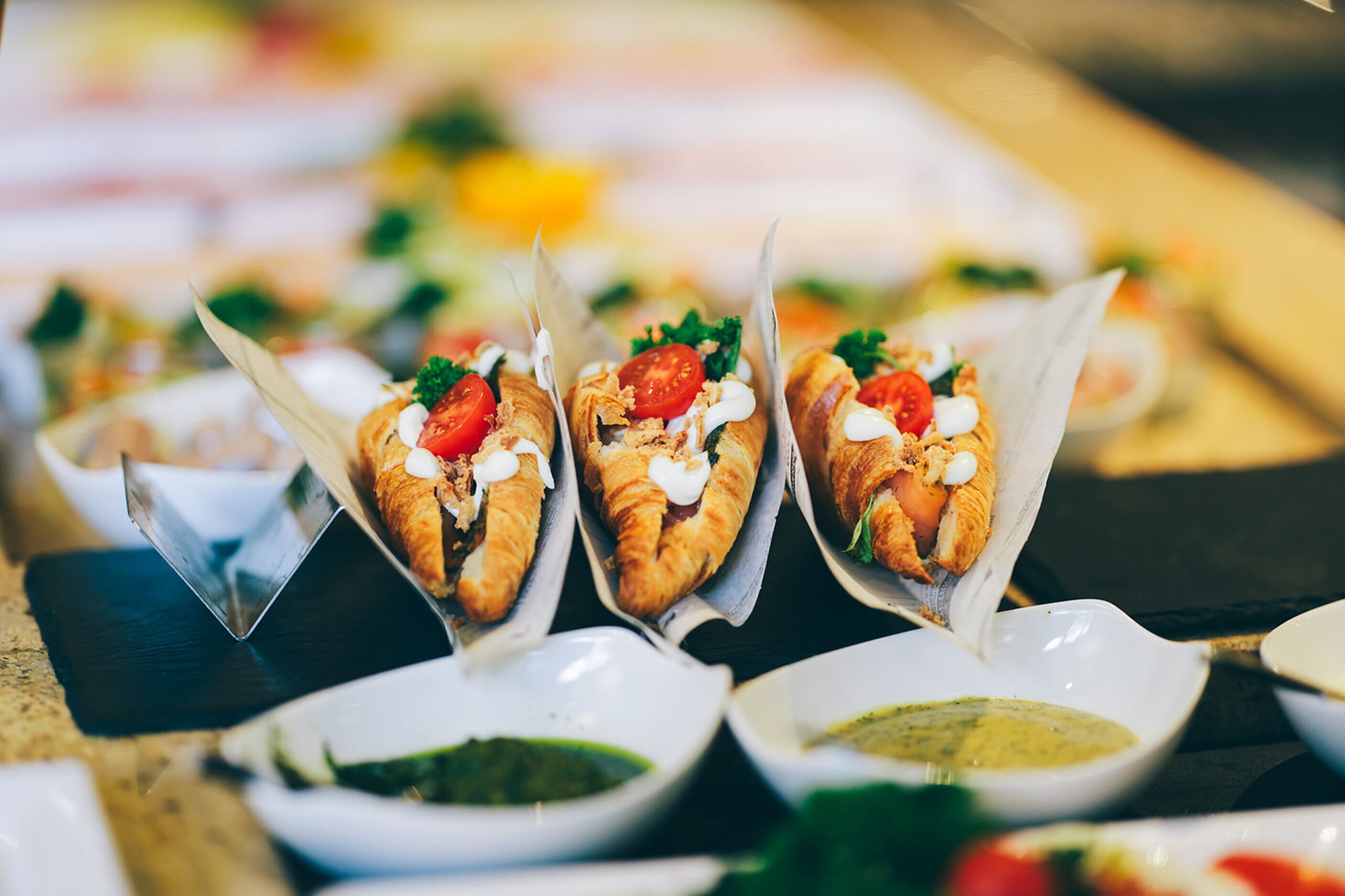 Diverse etenswaren, waaronder sandwiches en kleine schaaltjes met sauzen, op een tafel gerangschikt.