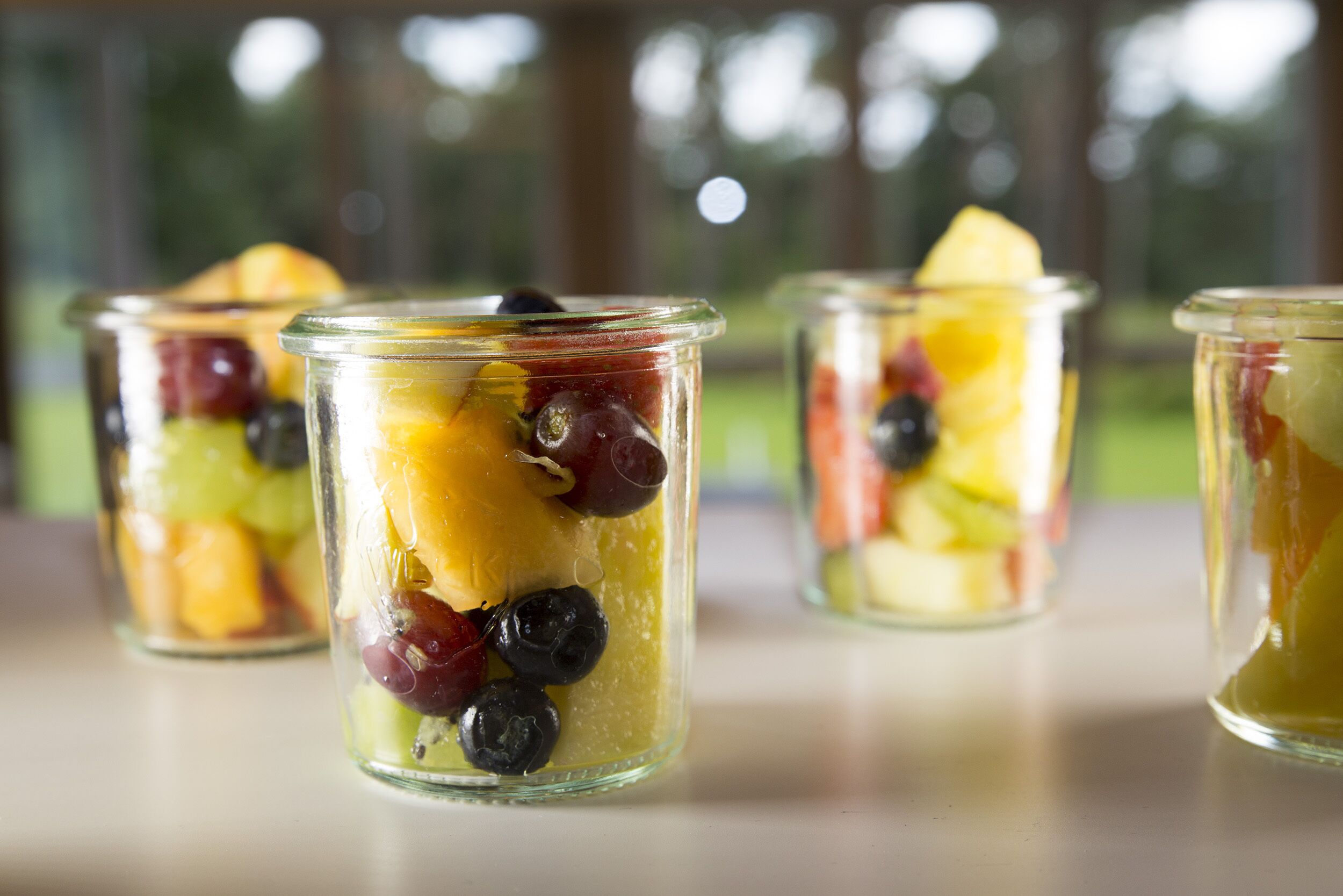 Four glass containers with fruit salad.