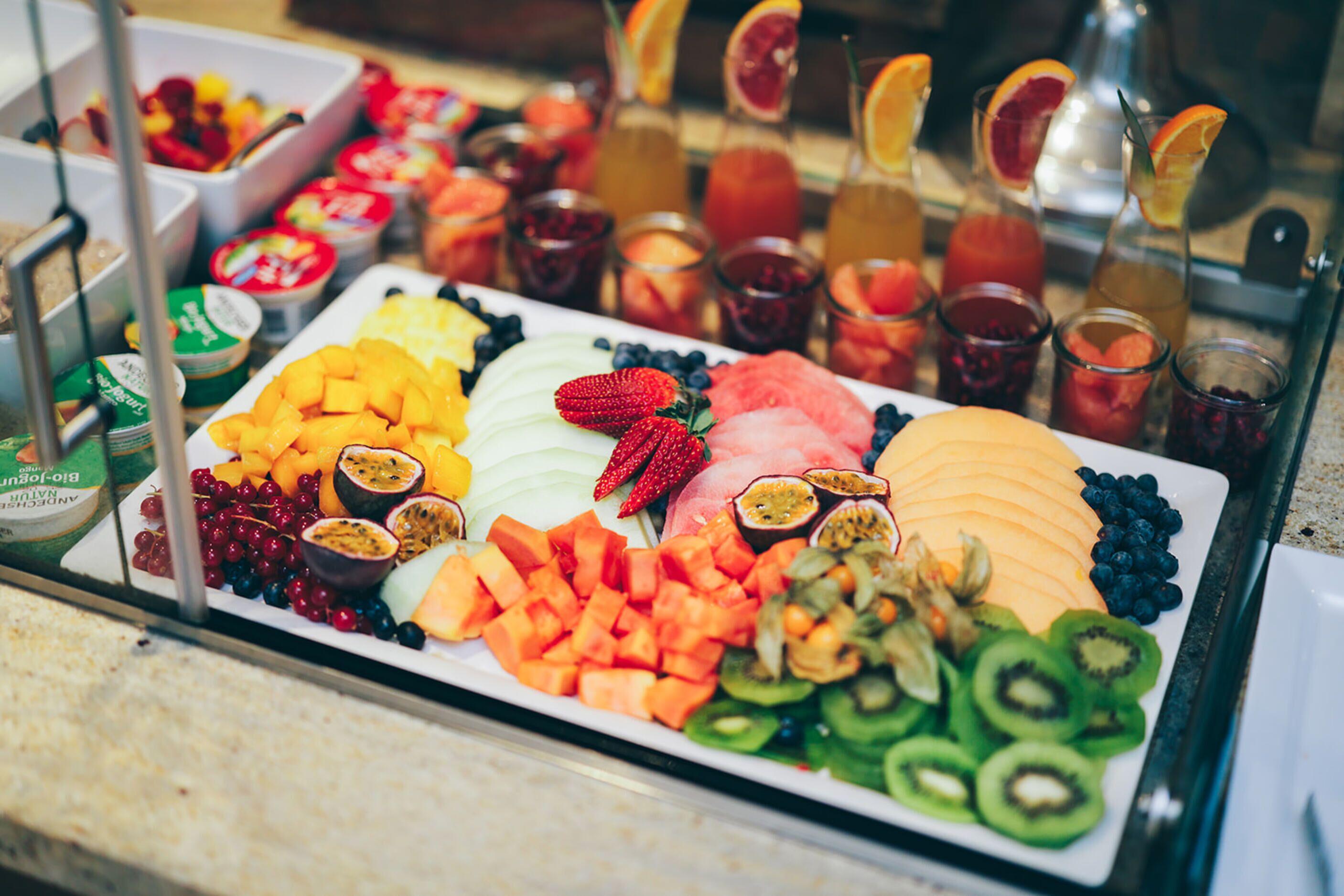 A fruit platter with various sliced fruits and a selection of beverages.