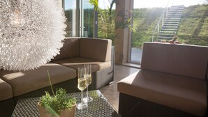 Una sala de estar moderna con un sofá, una mesa de centro con una planta en maceta y dos copas de vino blanco.