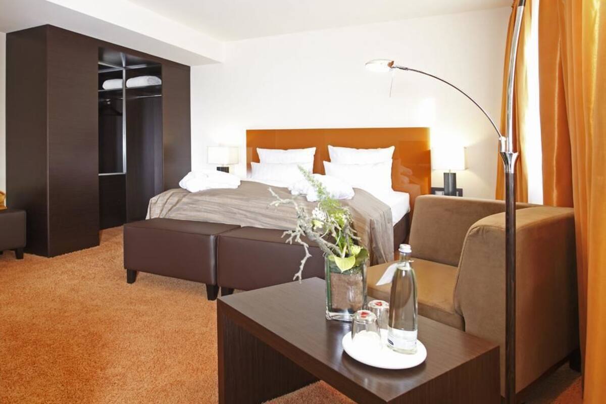 Une chambre d’hôtel comprenant un lit, des tables de chevet, un canapé, un bureau et une armoire.