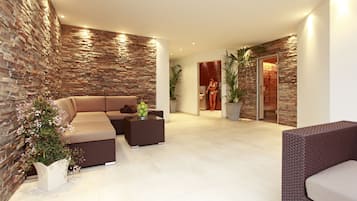 Un salón moderno con una pared de piedra, un sofá color beige, una mesa de centro y plantas en macetas.