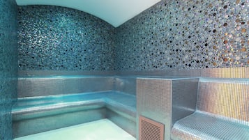 Relax in a serene spa room with a unique mosaic wall design, a seating area, and individual chairs.
