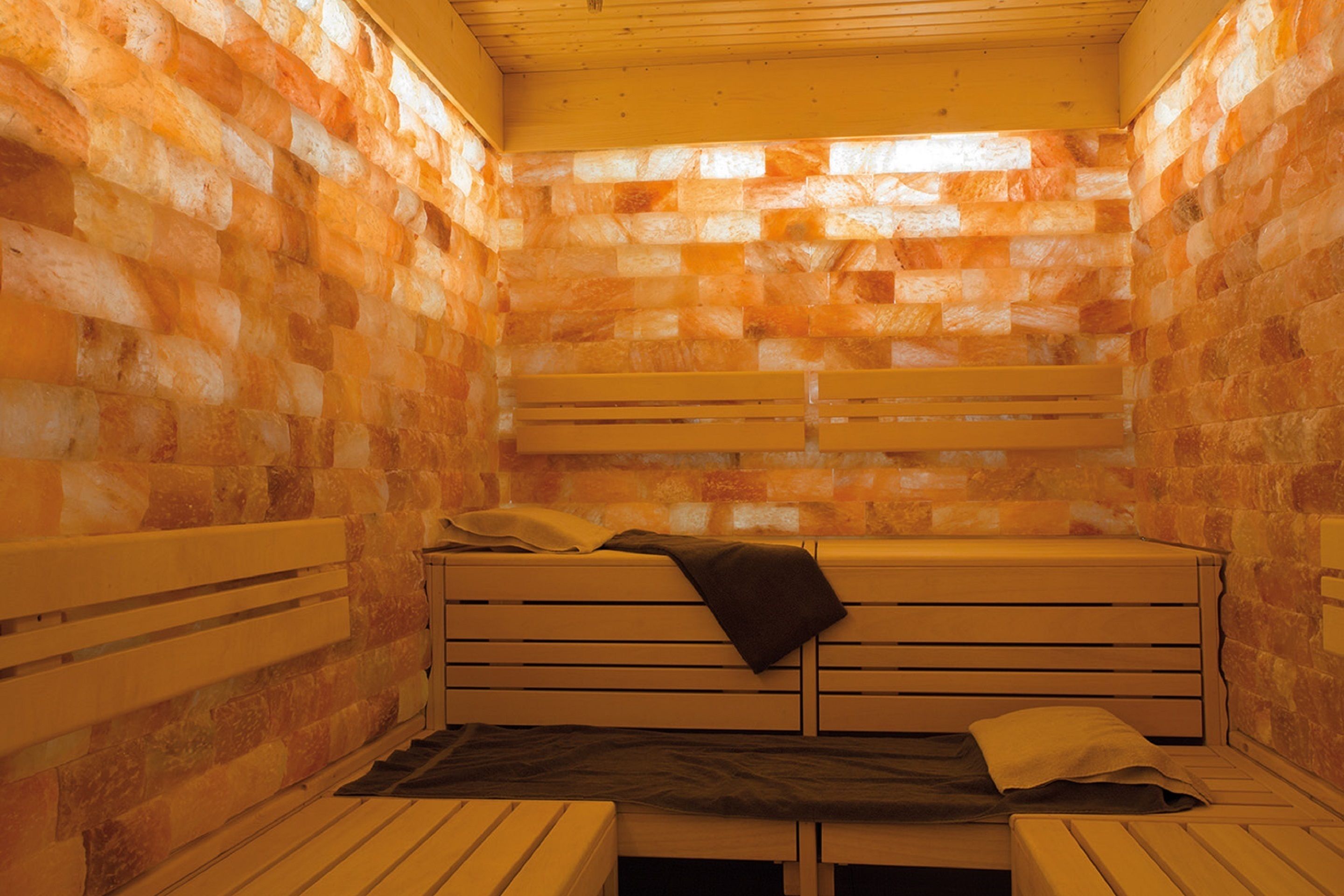 A sauna room with wooden benches and a stone wall.