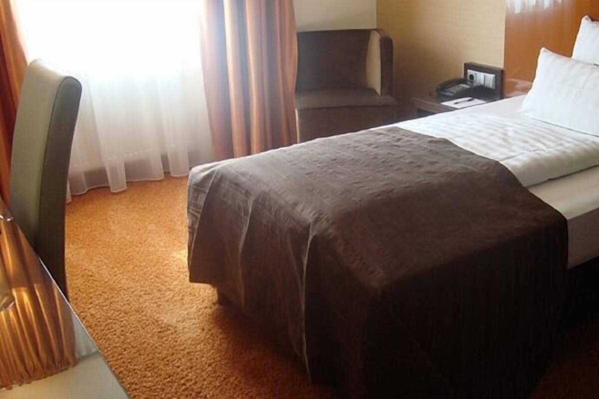Une chambre d’hôtel avec un lit, un bureau et une chaise.