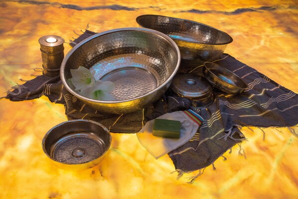 A collection of metal bowls and a candle on a patterned cloth.