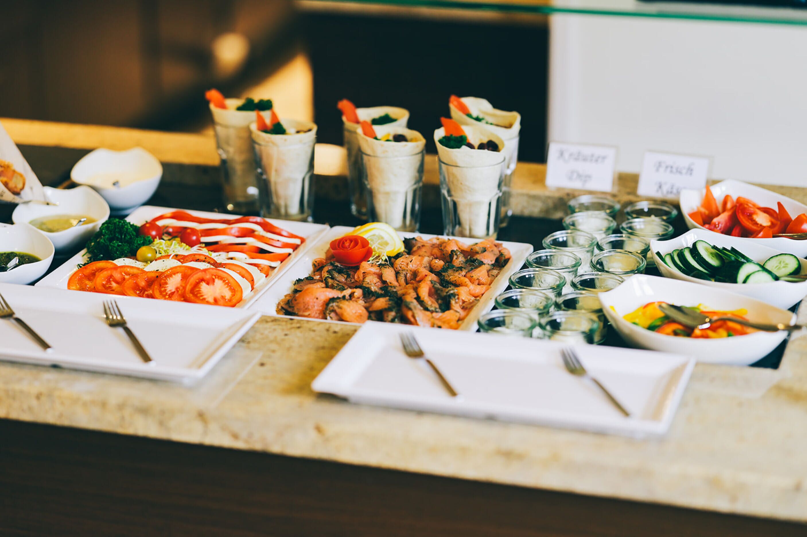 A buffet table with various dishes, including salads, meats, and dips.