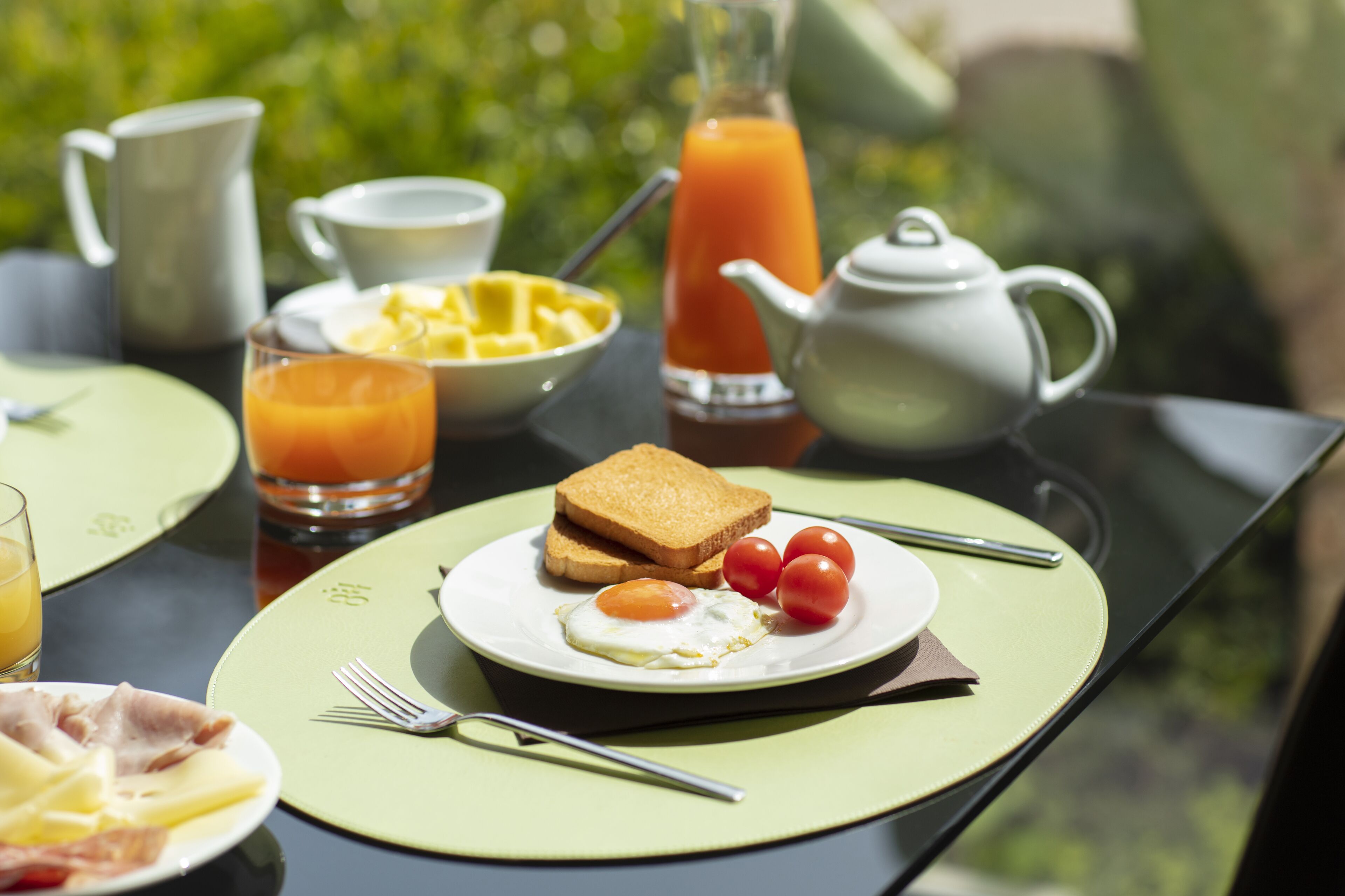 Una tavola imbandita per la colazione con pane tostato, uova, pomodori e succo di frutta.