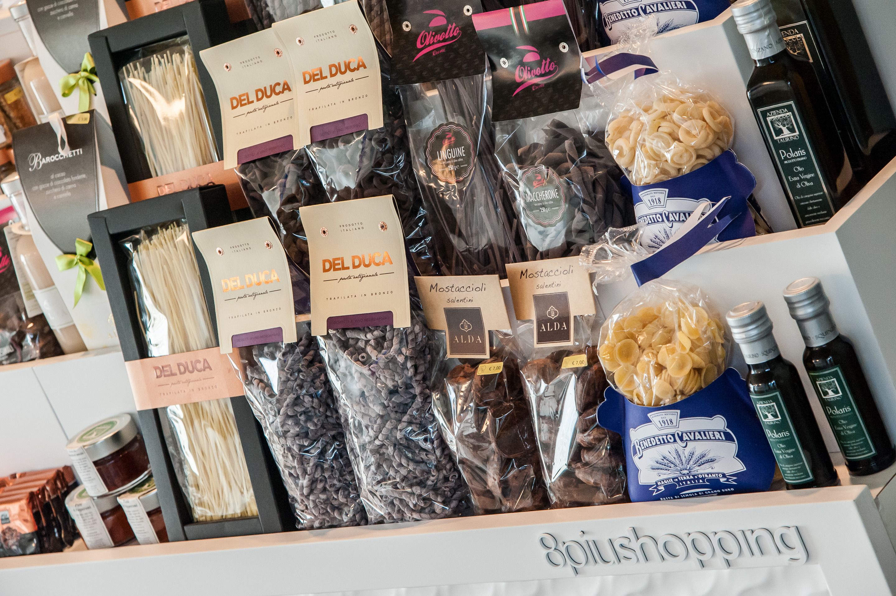 A display of various food products including pasta, chocolates, and olive oil.