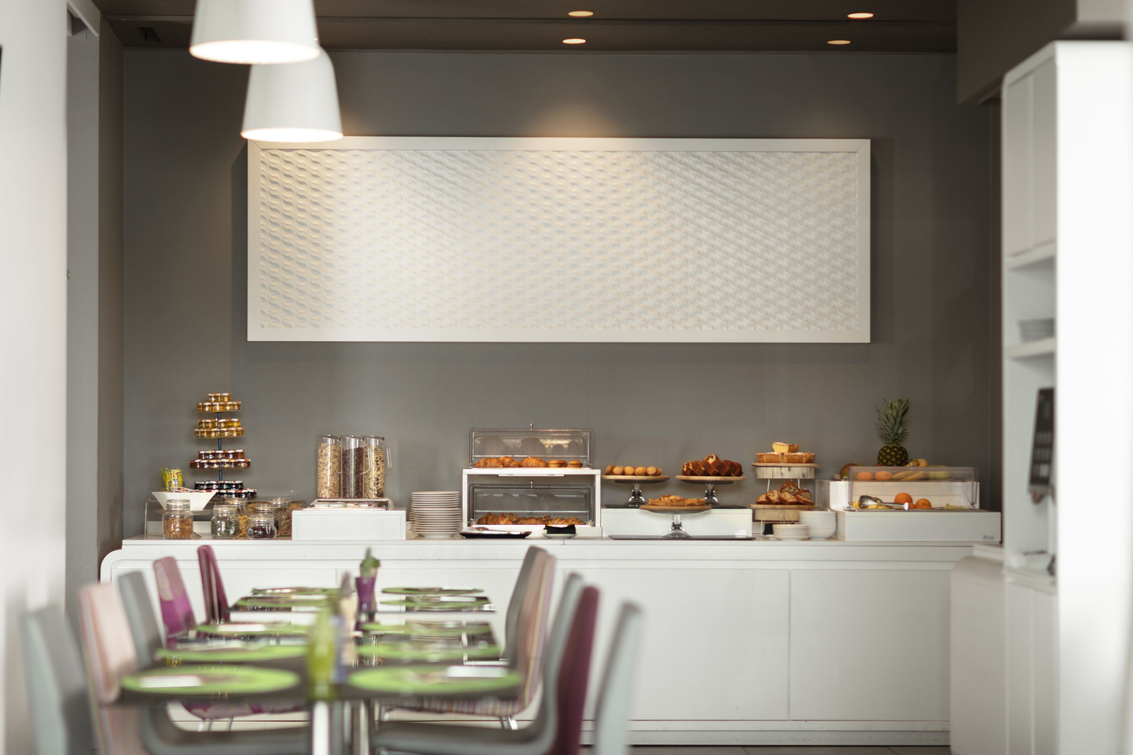 A modern breakfast bar with a variety of food items and a seating area with chairs.