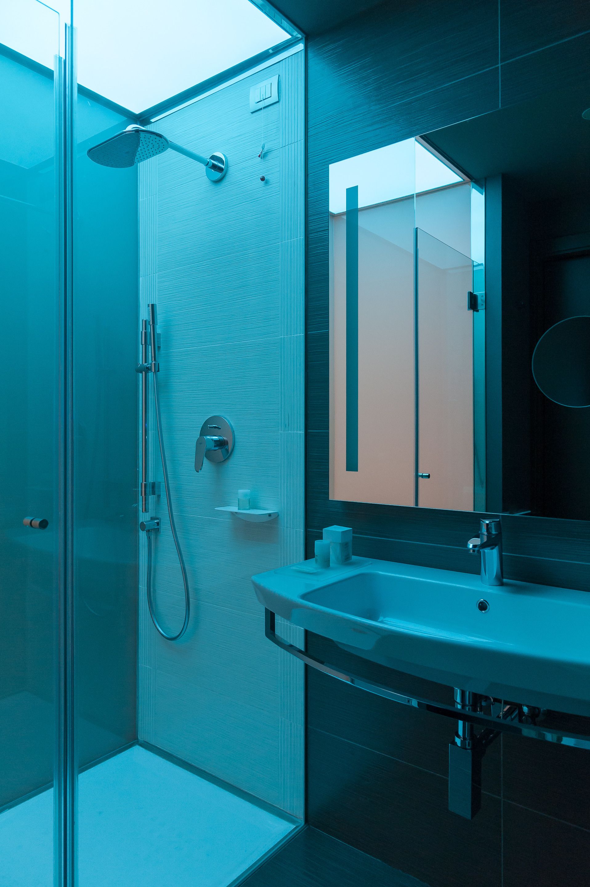 Un baño moderno con cabina de ducha de vidrio, lavabo con espejo y perchero para toallas.