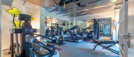 Un gimnasio moderno con diverso equipo de ejercicio, incluyendo cintas de correr, elípticas y máquinas de pesas.