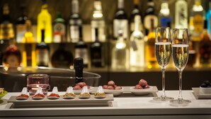 A bar setting with various bottles and glasses, including two champagne flutes filled with bubbles. - 8Piuhotel (Lecce)