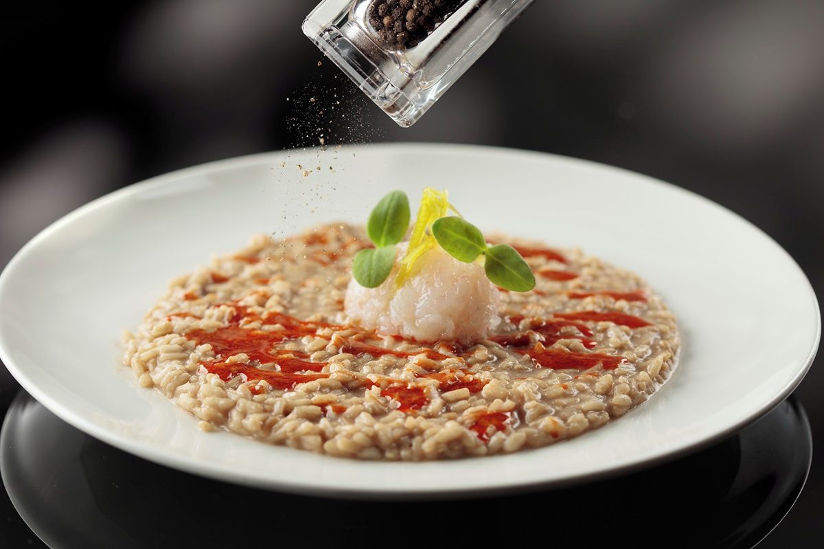 A plate of food with a clear focus on the dish, which includes a mound of rice, a dollop of sauce, and a garnish of green leaves.