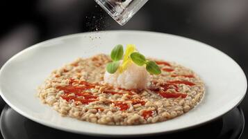 A plate of food with a clear focus on the dish, which includes a mound of rice, a dollop of sauce, and a garnish of green leaves.