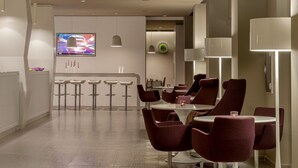 A modern hotel lobby with a bar area, seating arrangements, and a flat-screen TV. - 8Piuhotel (Lecce)