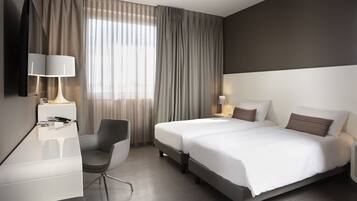 Una habitación de hotel moderna con una cama, mesitas de noche, un escritorio y una silla.