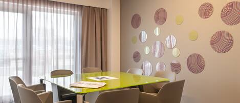 A conference room with a glass table, beige chairs, and patterned wall decorations.