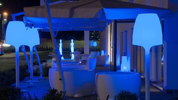 Un espacio al aire libre con mobiliario blanco moderno e iluminado con luces azules.