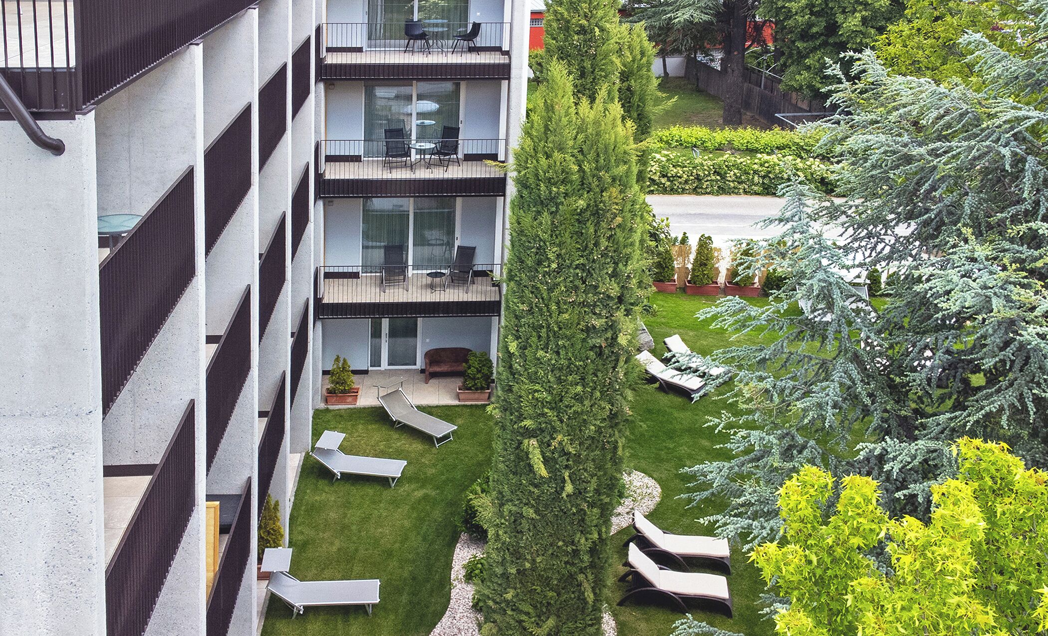 A multi-story residential building with balconies, outdoor seating, and a well-maintained garden.