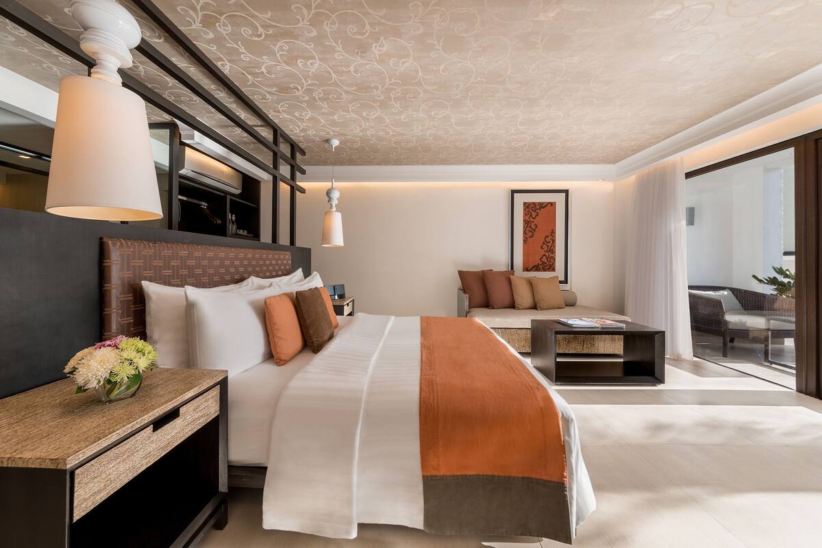 Et moderne hotelværelse med en stor seng, en sofa, et lille bord og et sengebord.