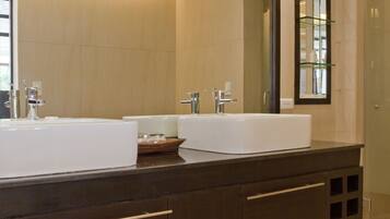 A modern bathroom with two large white sinks, dark wooden cabinets, and a large mirror.
