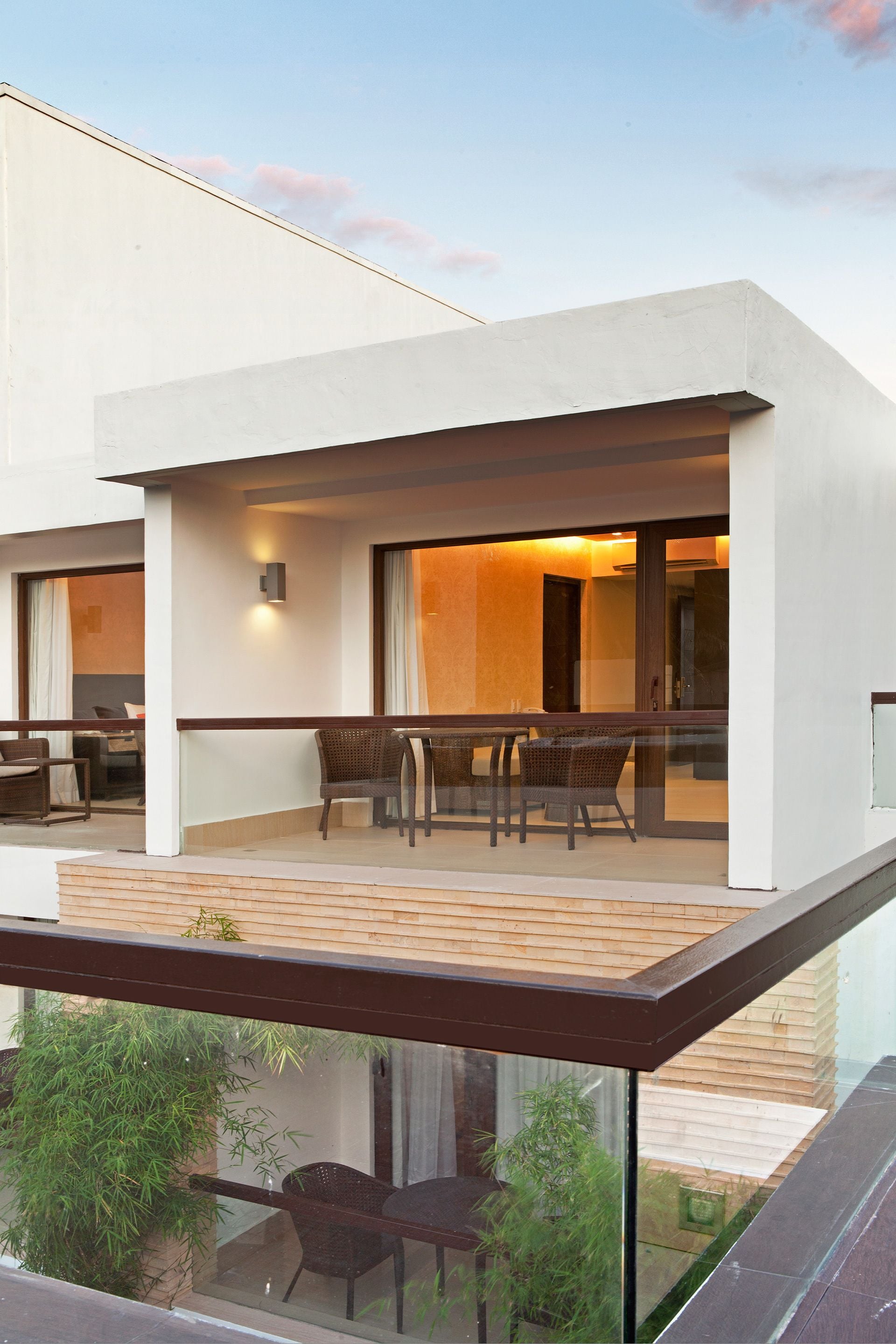 A modern building with a balcony, outdoor seating, and a glass railing.