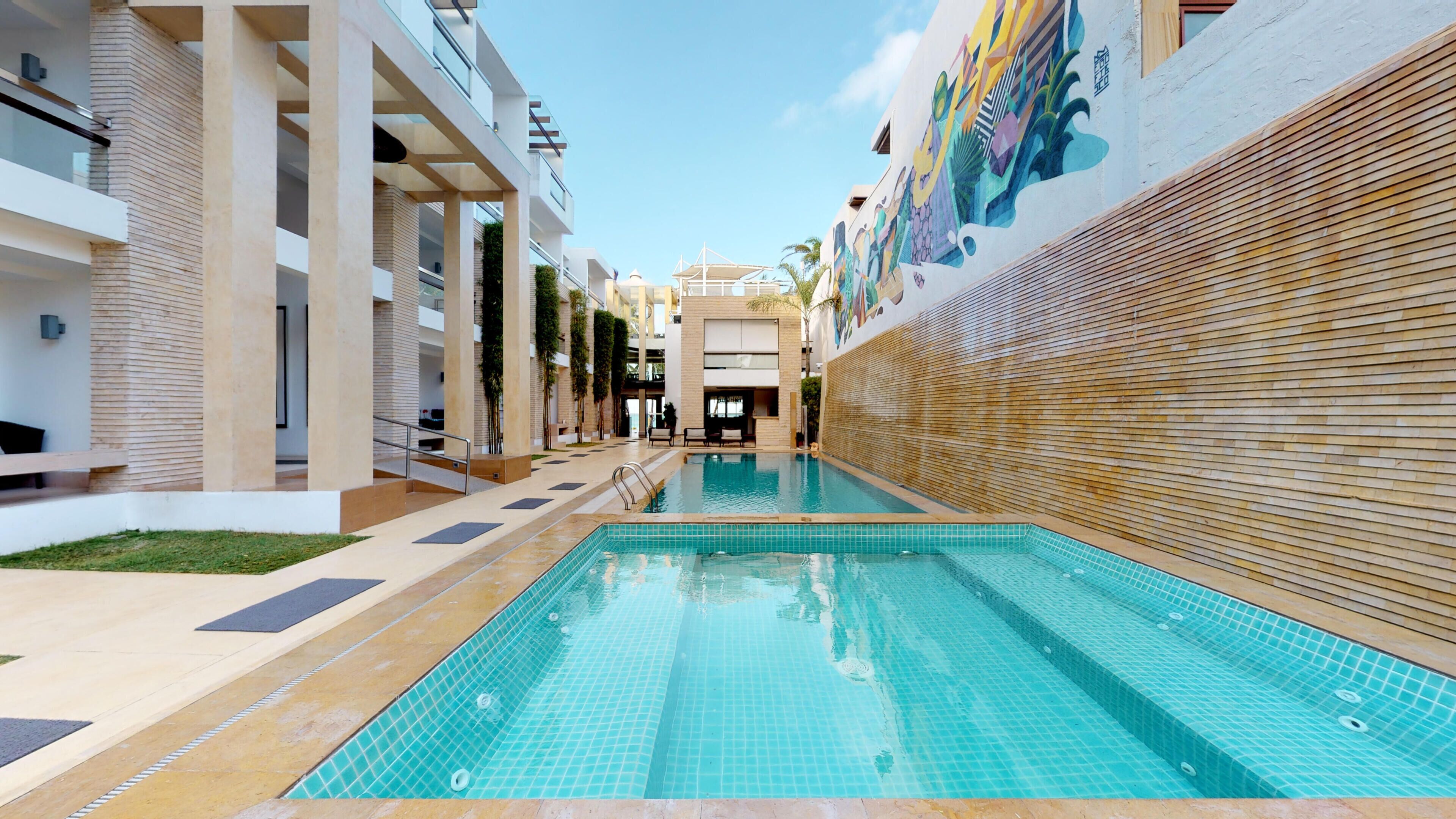 Una piscina al aire libre, sombrillas, sillones reclinables de piscina
