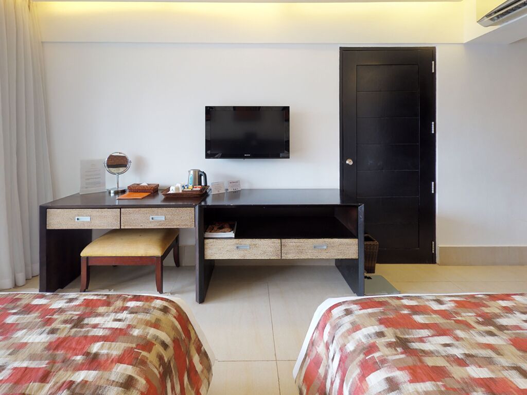 A hotel room with a bed, a desk with a chair, a television, and a wardrobe.