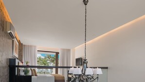 Un intérieur moderne avec un escalier menant à un espace de vie, un lustre et une vue sur des palmiers.