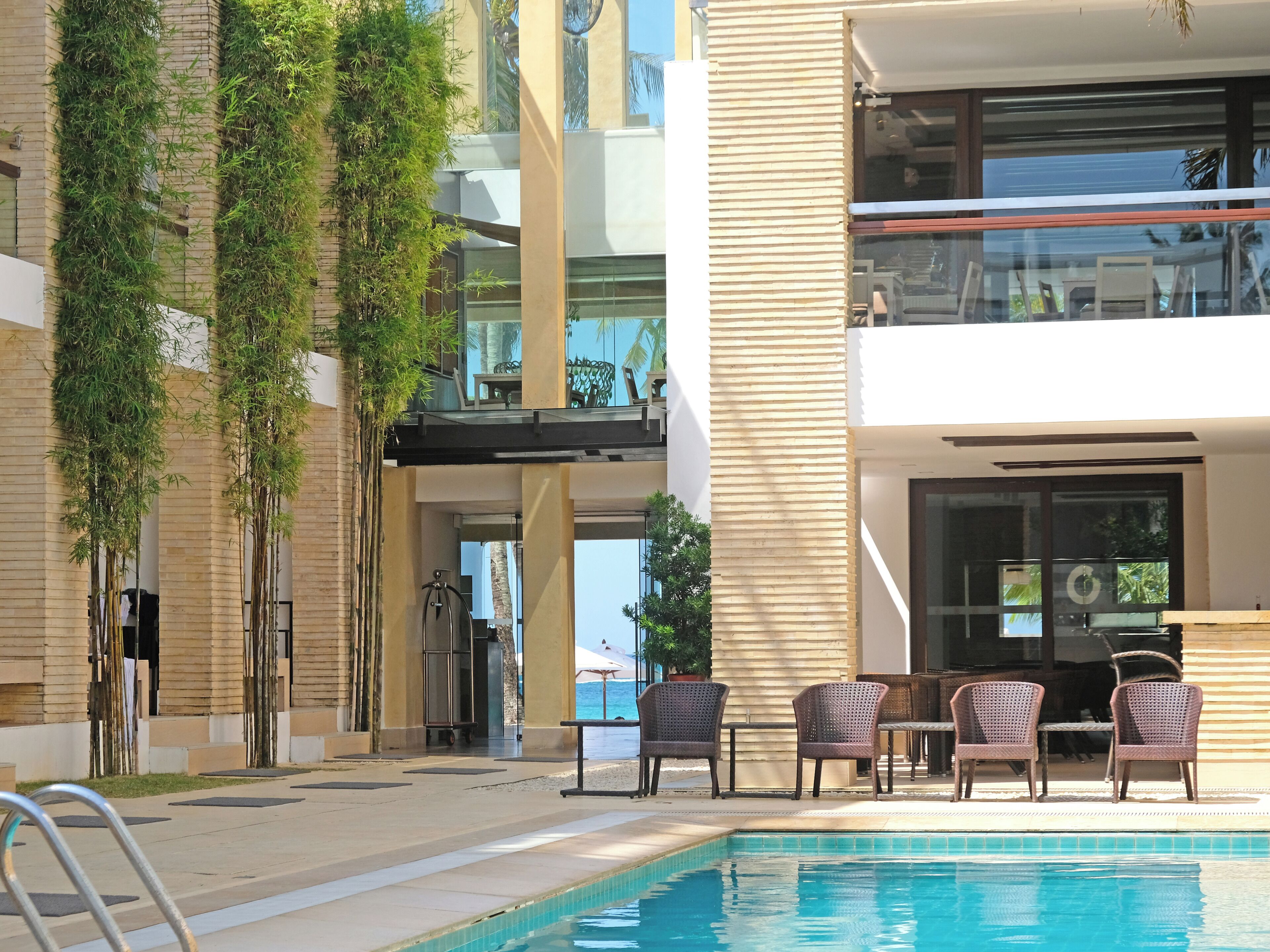 Un área de piscina con sillones de descanso y vista a un edificio con balcón.