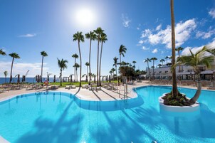 A swimming pool with palm trees and a clear sky.