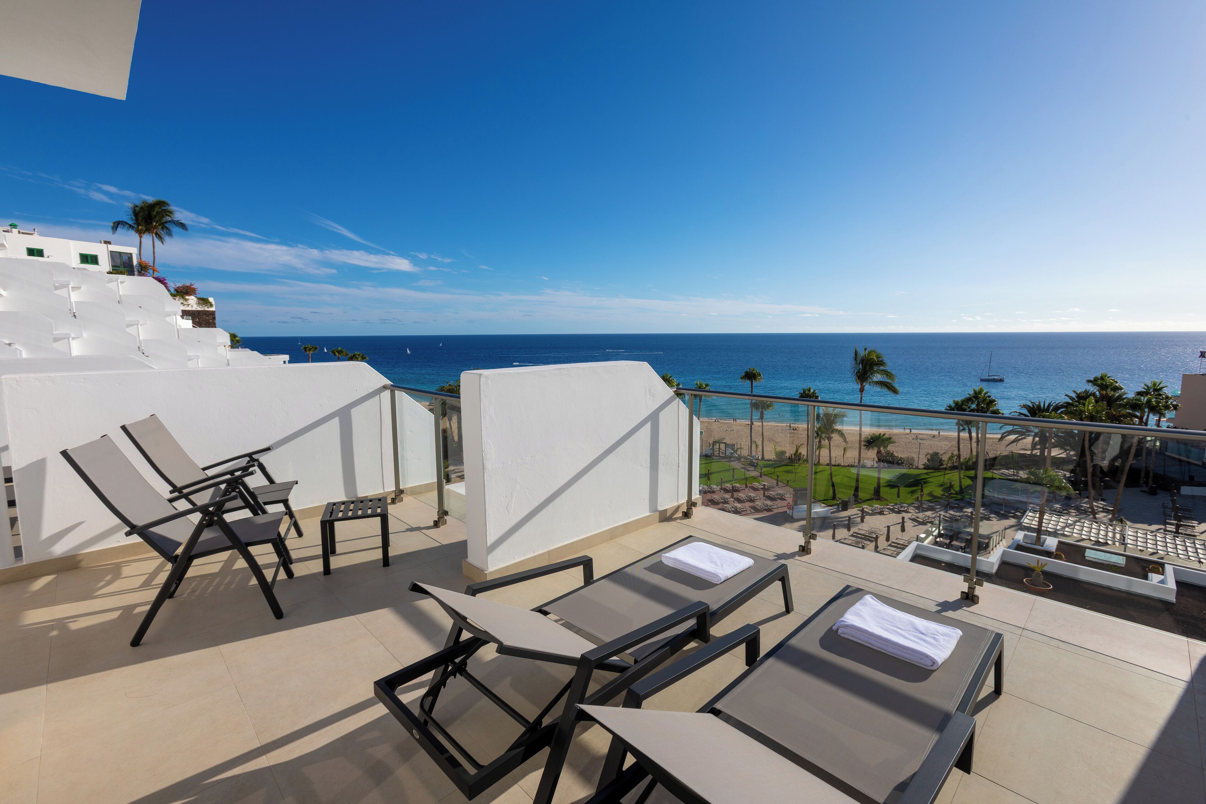 Eine Dachterrasse mit Liegestühlen und Blick auf das Meer.